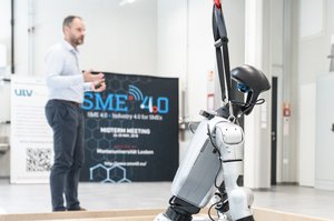 Quality management at the university. Photo: © TU Leoben A few people are standing in a laboratory. A seated robot can be seen in the foreground.