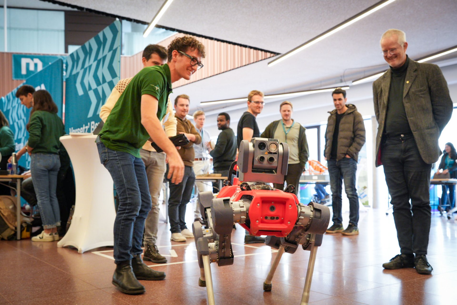 Studienberatung, Workshops und Campus-Führungen warten auf dich beim Info-Tag. Foto: © MUL Die Besucher*innen des Info-Tags beobachten fasziniert einen Roboter.