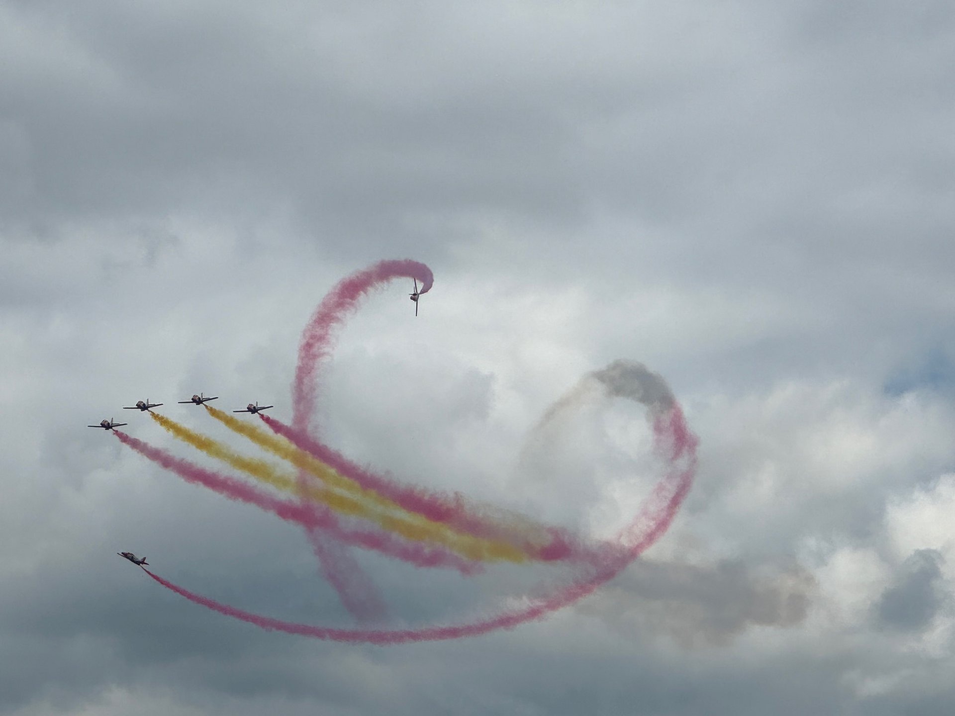 Flugezeuge mit roten und gelben Kondensstreifen anlässlich der Flugshow AirPower 2024 in Zeltweg.