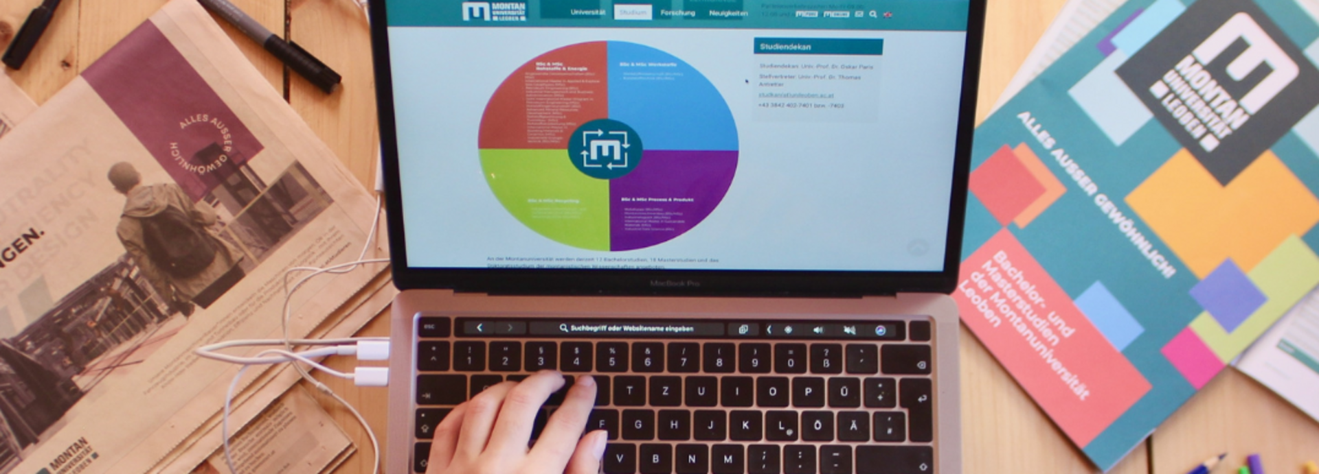Ein Laptop liegt auf den Beinen einer Studentin und sie surft auf der Website der Montanuniversität.