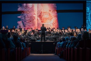 Das Universitätsblasorchester bei einem Konzert. Foto: © MUL/Thomas Fazokas Das Universitätsblasorchester bei einem Konzert auf der Bühne. Der Dirigent steht mit dem Rücken zum Publikum.