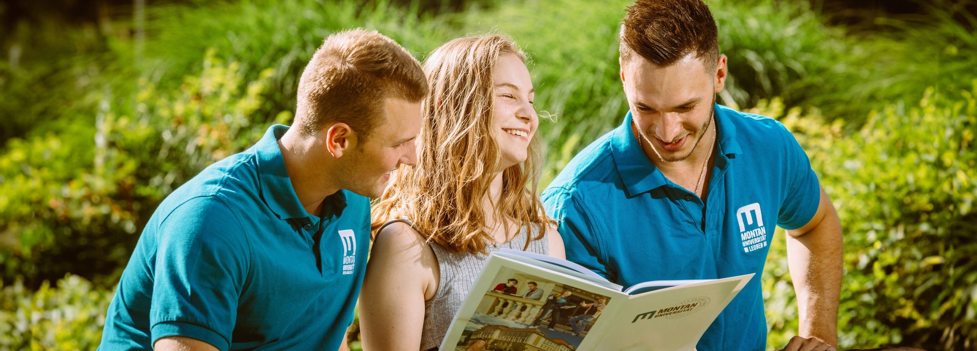 Eine Studentin und zwei Studenten im Park der Universität.