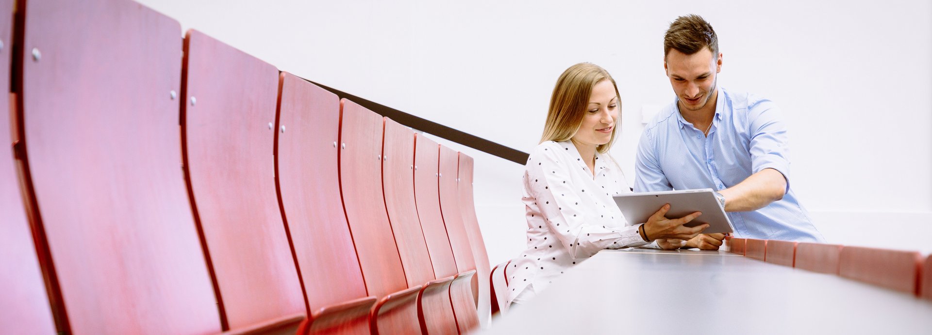 Studieninteressierte sitzen in einem Hörsaal und sehen auf einen Laptop.