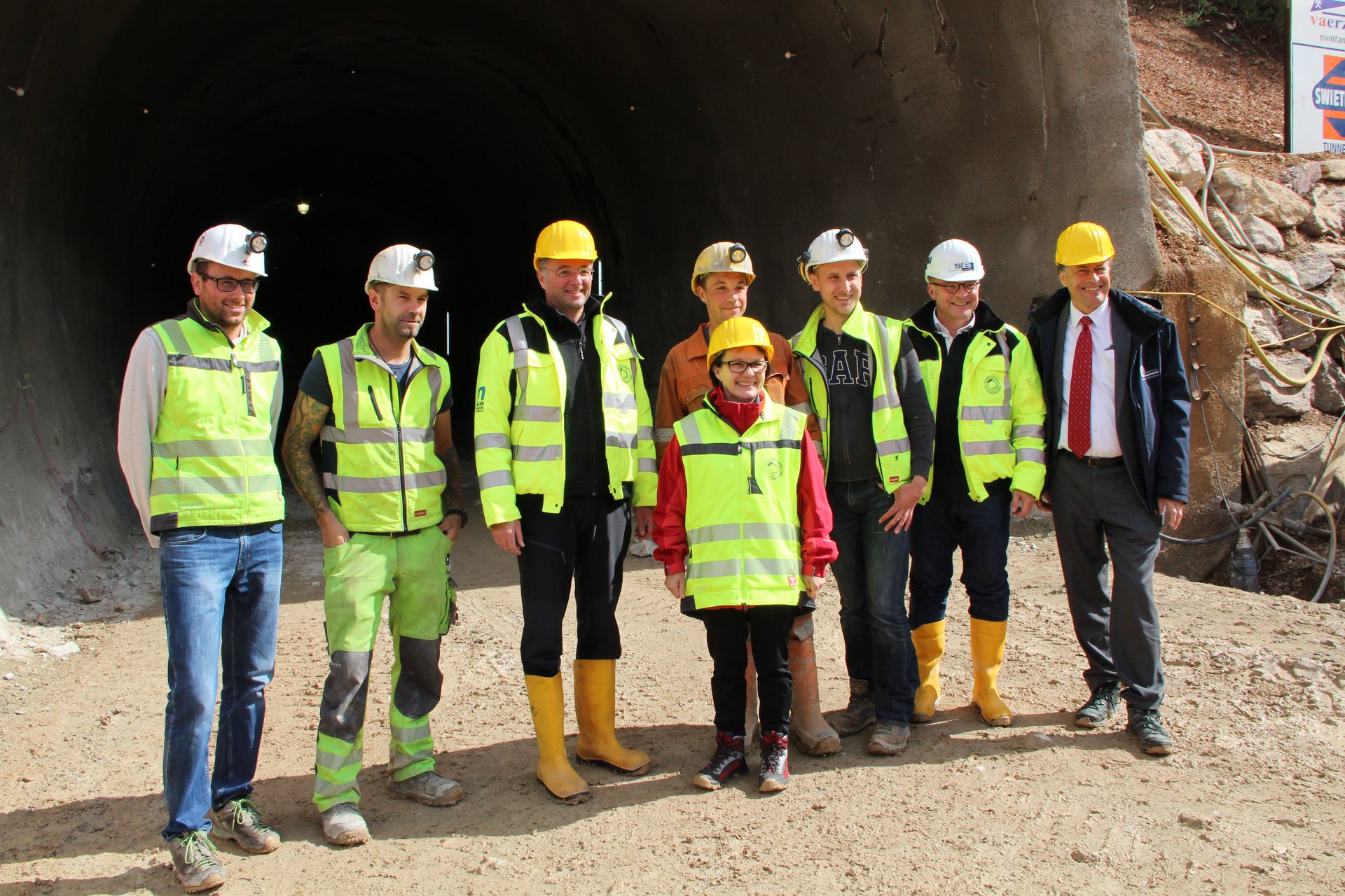 Personengruppe mit Schutzhelmen vor Stolleneingang, darunter u. a. Infrastrukturminister Mag. Jörg Leichtfried, Vizerektorin Martha Mühlburger, ZaB-Leiter Univ.-Prof. Robert Galler, Rektor Wilfried Eichsleder