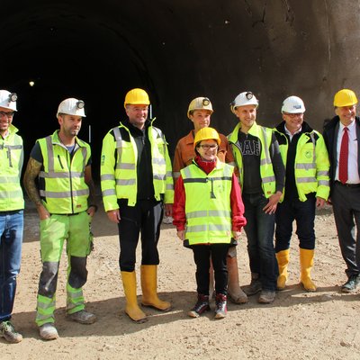 Personengruppe mit Schutzhelmen vor Stolleneingang, darunter u. a. Infrastrukturminister Mag. Jörg Leichtfried, Vizerektorin Martha Mühlburger, ZaB-Leiter Univ.-Prof. Robert Galler, Rektor Wilfried Eichsleder