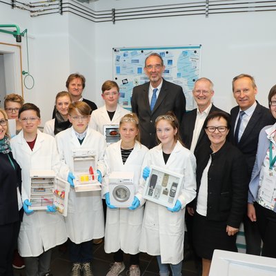 Gruppenbild mit Bundesminister Heinz Faßmann (Mitte) sowie Vertretern der Montanuniversität Leoben und der Kirchlichen Pädagogischen Hochschule Graz im Kreise von jungen Forscherinnen und Forscher in einem Labor