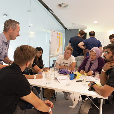 Gruppe von Menschen, die in einem Büro eine Besprechung abhalten anlässlich des Innovationsmarathons der TU Austria.