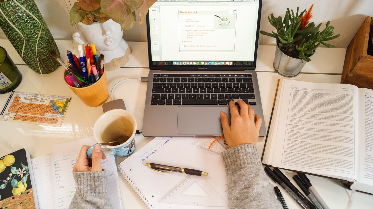 Women's hands with a coffee cup in front of a laptop screen.