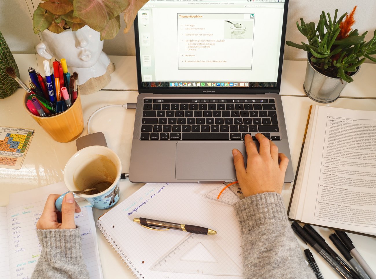 Women's hands with a coffee cup in front of a laptop screen.